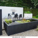 garden with modern garden furniture and trendy pond - stock image BNNASRF