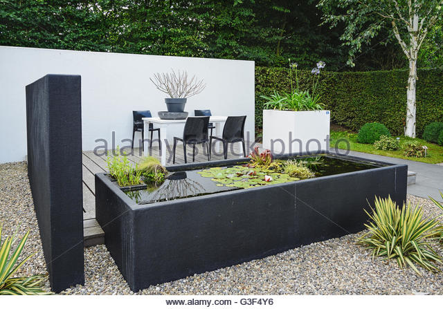 garden with modern garden furniture and trendy pond - stock image BNNASRF