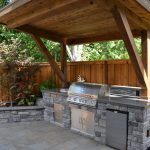 rustic patio with polished concrete, outdoor kitchen, raised beds, stacked  stone, fence UTDEMWZ