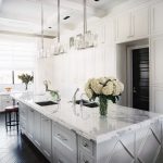 A beautiful white kitchen with dark flooring. The countertops are .