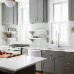 Gray kitchen cabinet color with white trim and white countertops .