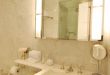 Elegant bathroom features hollywood style vanity mirror over white .