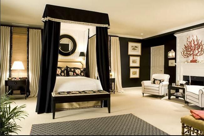 THIS BLACK AND WHITE BEDROOM BOASTS A LUXURIOUS DRAPED CANOPY .