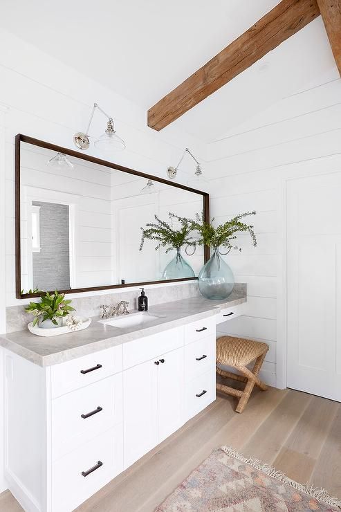 Cottage master bathroom designed with a seagrass x stool under a .